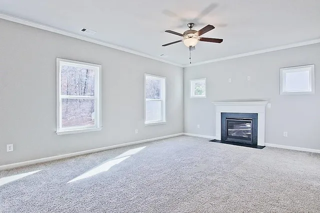 a view of an empty room with a fireplace and a ceiling fan