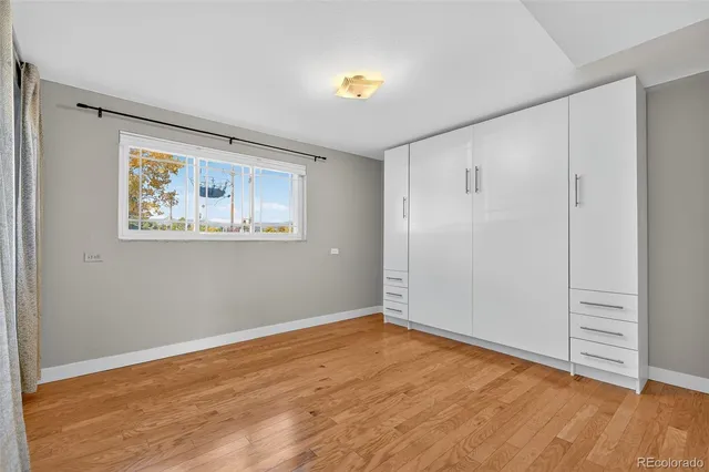 a view of an empty room with wooden floor and window