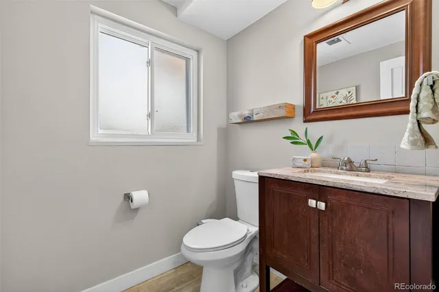 a bathroom with a granite countertop toilet sink and mirror