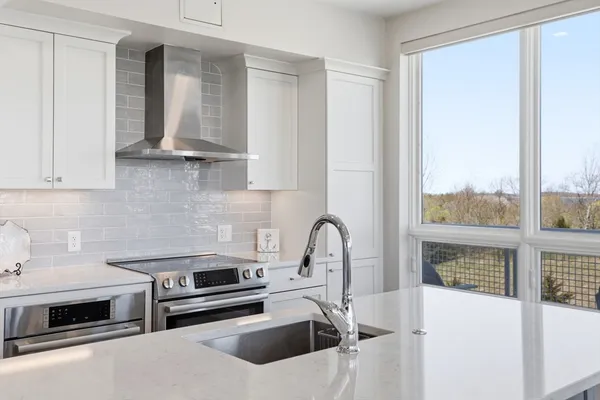 a kitchen with stainless steel appliances a stove a sink and a white cabinets