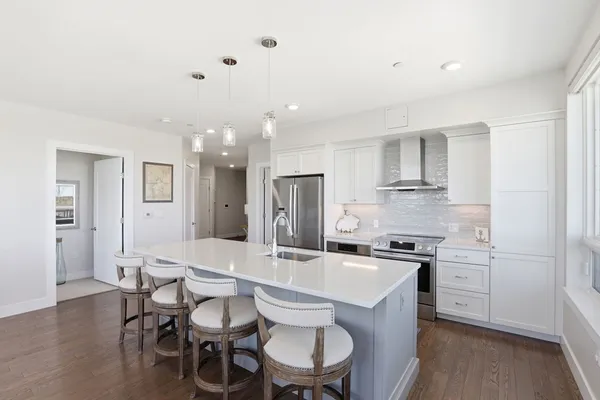 a kitchen with stainless steel appliances a dining table chairs and wooden floor