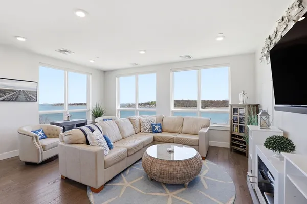 a living room with furniture a rug a flat screen tv and a large window