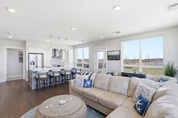 a living room with furniture kitchen view and a large window