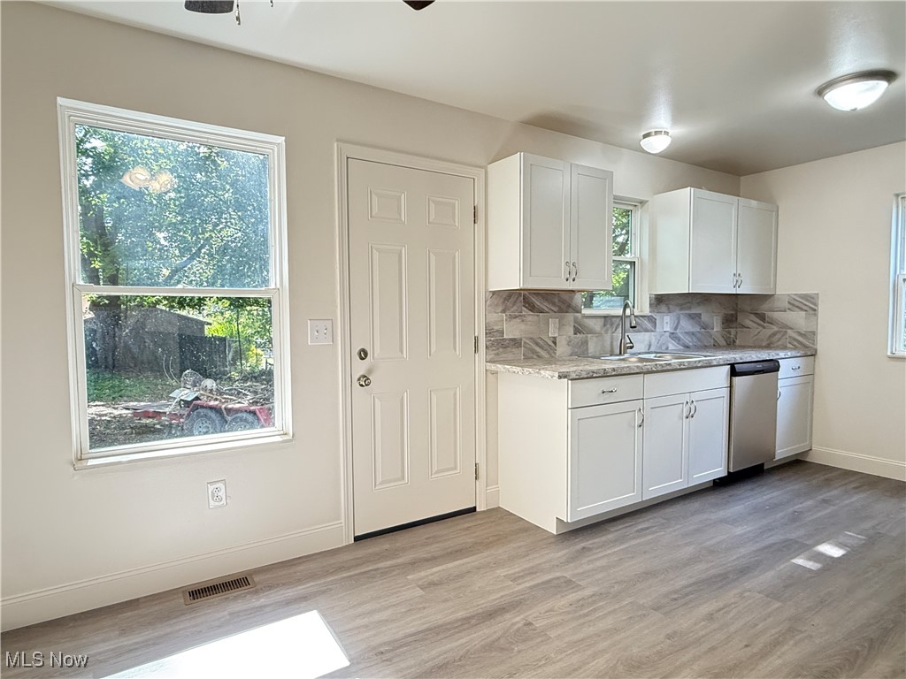 247 Reed Avenue Campbell, OH 44405 - Photo 12 of 41 Kitchen with white cabinets, tasteful backsplash, stainless steel dishwasher, and light wood-style flooring