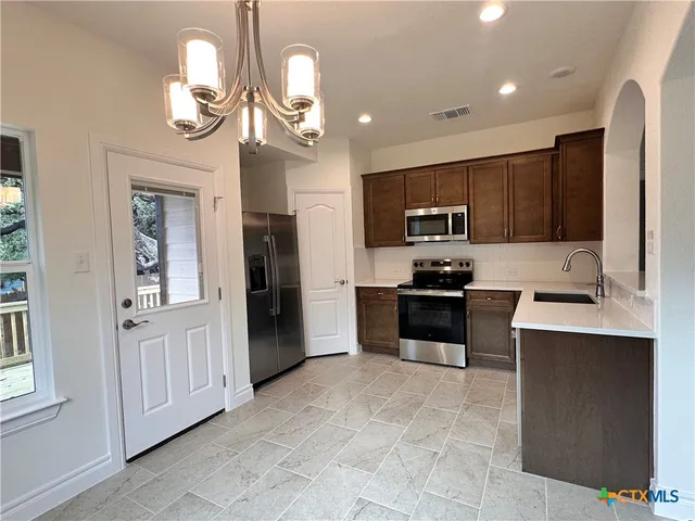 a kitchen with kitchen island granite countertop stainless steel appliances cabinets a sink and a counter top space
