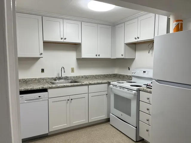 a kitchen with granite countertop white cabinets and a stove