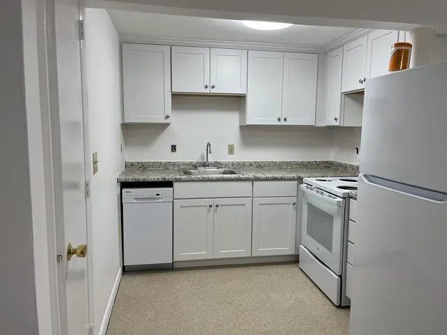 a kitchen with granite countertop white cabinets and white appliances