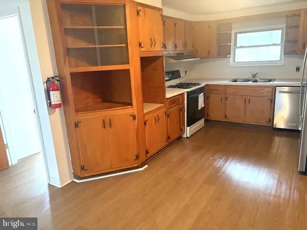 a kitchen with stainless steel appliances a stove a sink and white cabinets with wooden floor