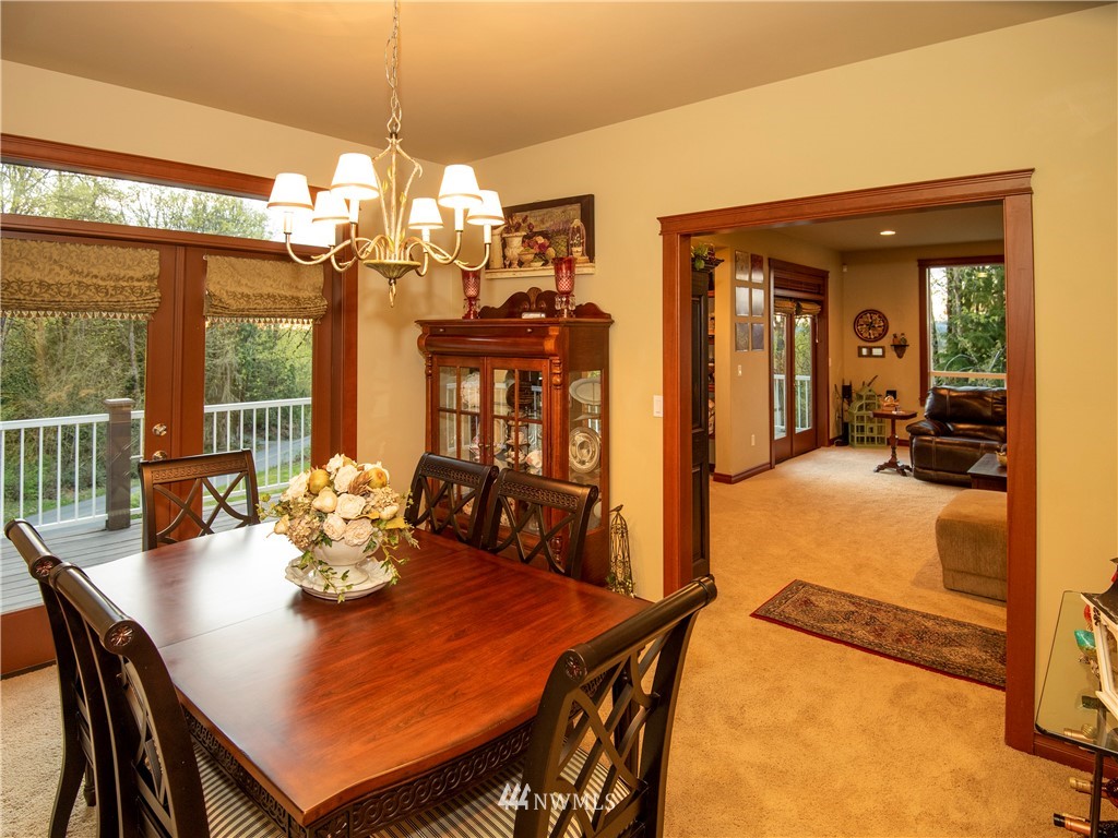 9415 Tveit Road Arlington, WA 98223 - Photo 14 of 28 a view of a dining room with furniture a chandelier and large windows