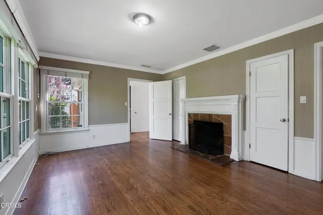 an empty room with wooden floor fireplace and windows