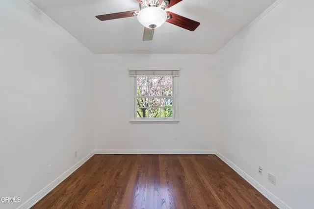 an empty room with wooden floor chandelier fan and windows