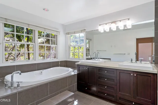 a bathroom with a tub a sink double vanity and a mirror