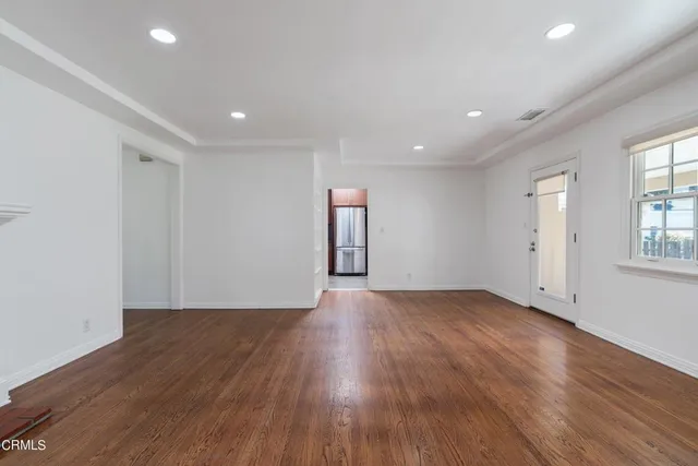 a view of an empty room with wooden floor and windows