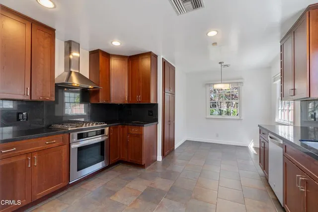 a kitchen with stainless steel appliances granite countertop a stove a sink and a refrigerator