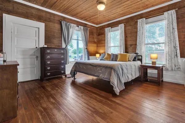 a bedroom with a bed and a large window with wooden floor