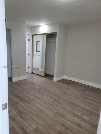 a view of an empty room with wooden floor and closet
