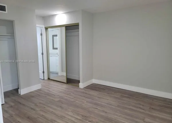 an empty room with wooden floor & closet area