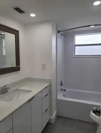 a bathroom with a granite countertop sink mirror toilet and bathtub