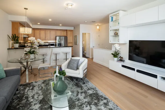 a living room with furniture a flat screen tv and kitchen view