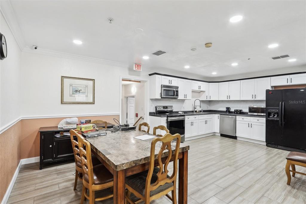 201 Rosefield Avenue Leesburg, FL 34748 - Photo 11 of 43 a kitchen with stainless steel appliances kitchen island granite countertop a refrigerator a stove top oven a sink dishwasher and white cabinets with wooden floor