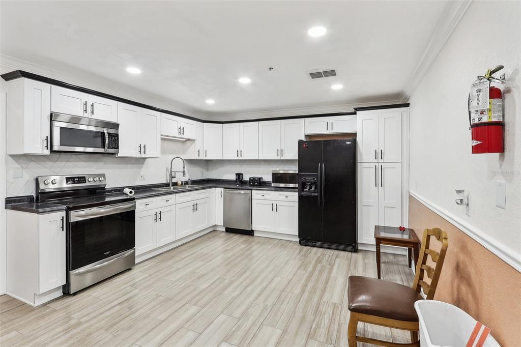 201 Rosefield Avenue Leesburg, FL 34748 - Photo 13 of 43 a large kitchen with a refrigerator a stove top oven a sink dishwasher and white cabinets with wooden floor