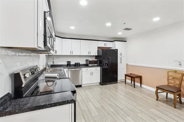 a kitchen with granite countertop wooden floors stainless steel appliances and sink