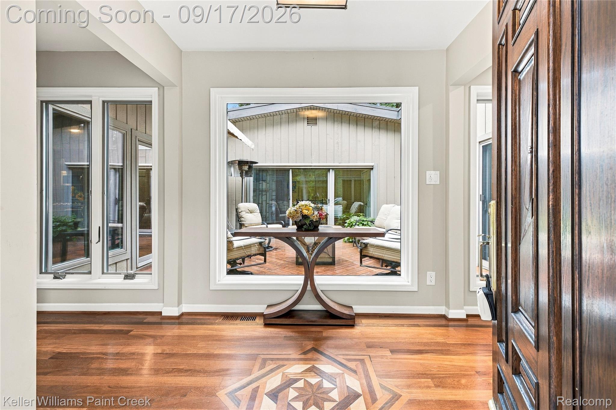 4535 Orion Road Rochester, MI 48306 - Photo 17 of 67 Wood-finish flooring with an inlaid geometric design, a dark wood-paneled door, and multiple large windows providing abundant natural light