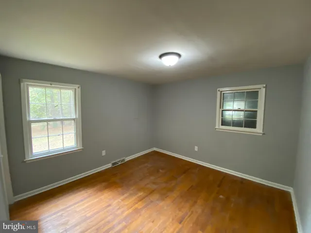 an empty room with wooden floor and windows with walls