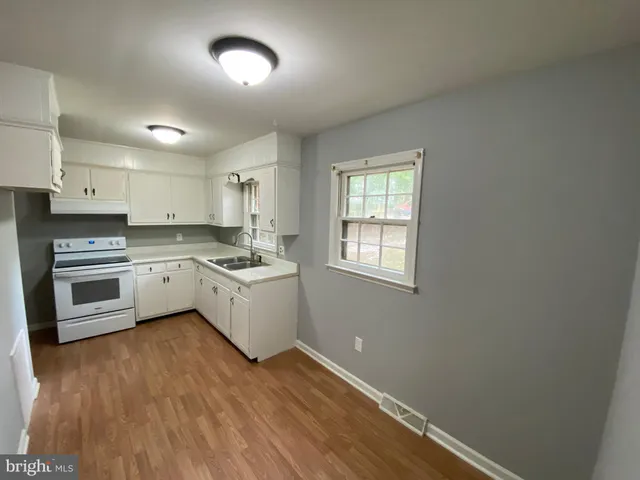 an empty room with kitchen appliances and wooden floor