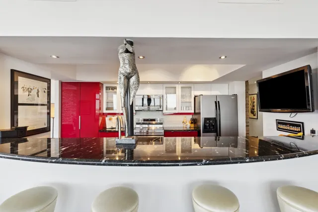 a kitchen with stainless steel appliances kitchen island granite countertop a sink and a flat screen tv