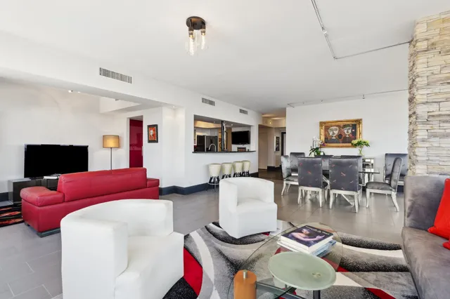 a living room with furniture a flat screen tv and kitchen view