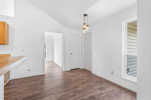 an empty room with wooden floor chandelier fan and windows