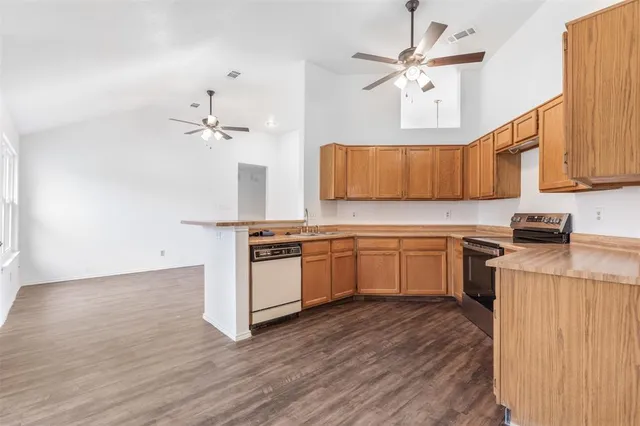 a kitchen with stainless steel appliances granite countertop wooden cabinets a sink a stove a dining table and chairs