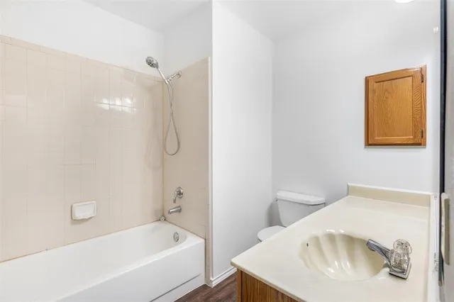 an empty room with wooden floor chandelier fan and windows