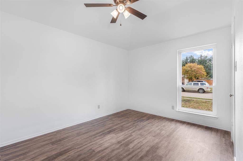 1313 Clover Drive Allen, TX 75002 - Photo 22 of 30 an empty room with wooden floor chandelier fan and windows