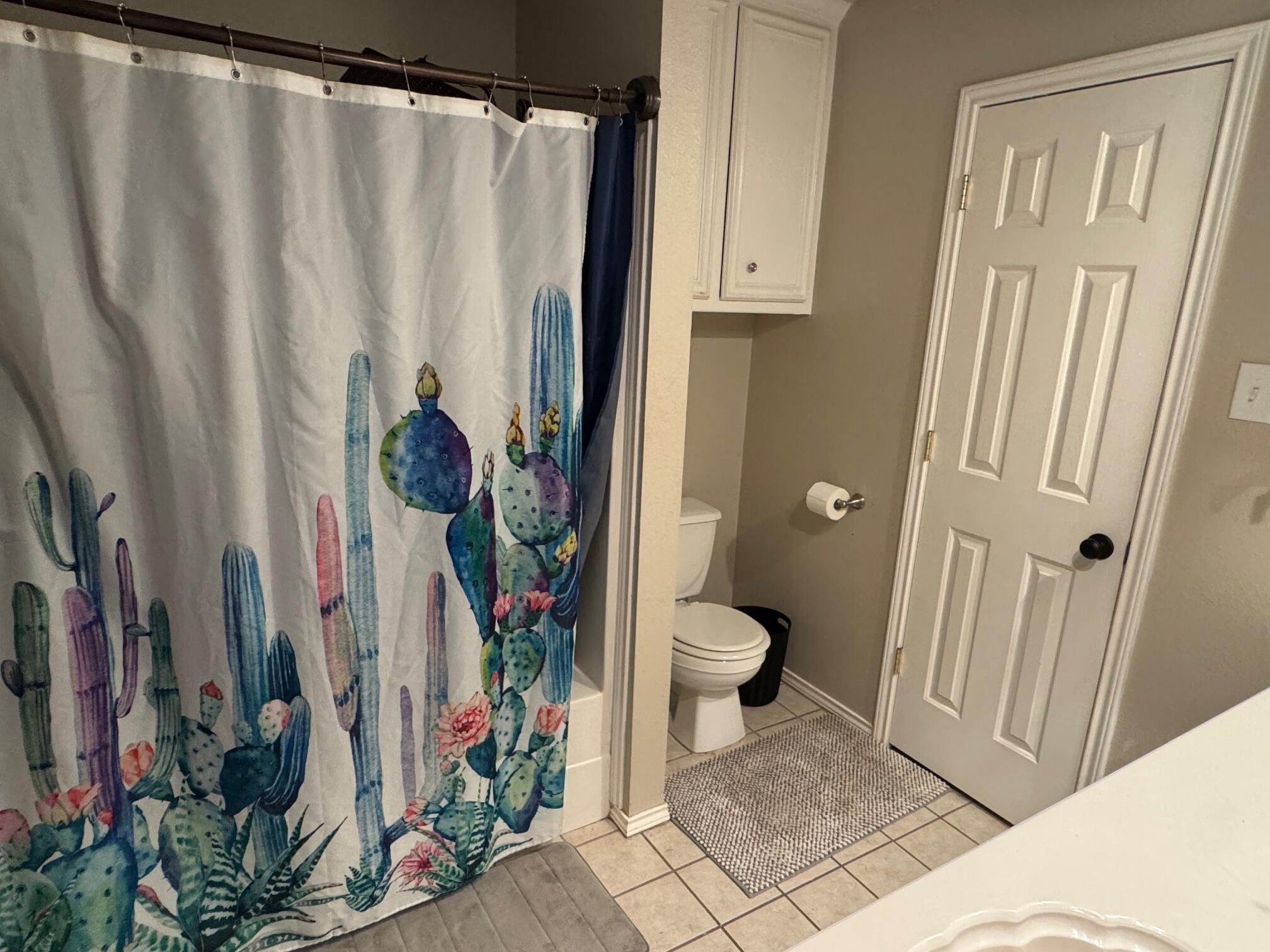1906 81st Street Lubbock, TX 79423 - Photo 6 of 14 a bathroom with a toilet and a shower curtain