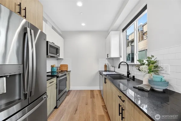 a kitchen with stainless steel appliances granite countertop a sink a stove and a refrigerator
