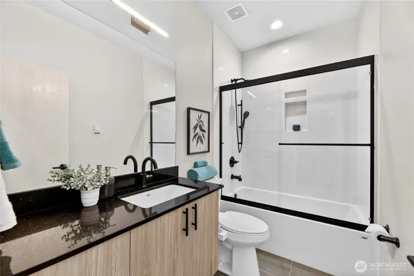 a bathroom with a granite countertop sink toilet and shower