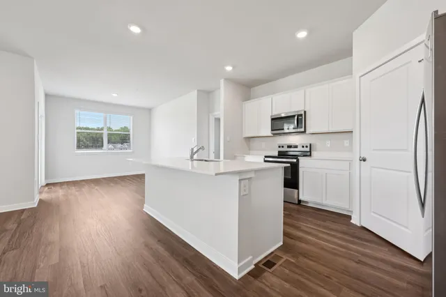 a kitchen with white cabinets and wooden floor