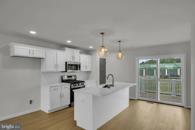 a large white kitchen with a large window a sink and stainless steel appliances