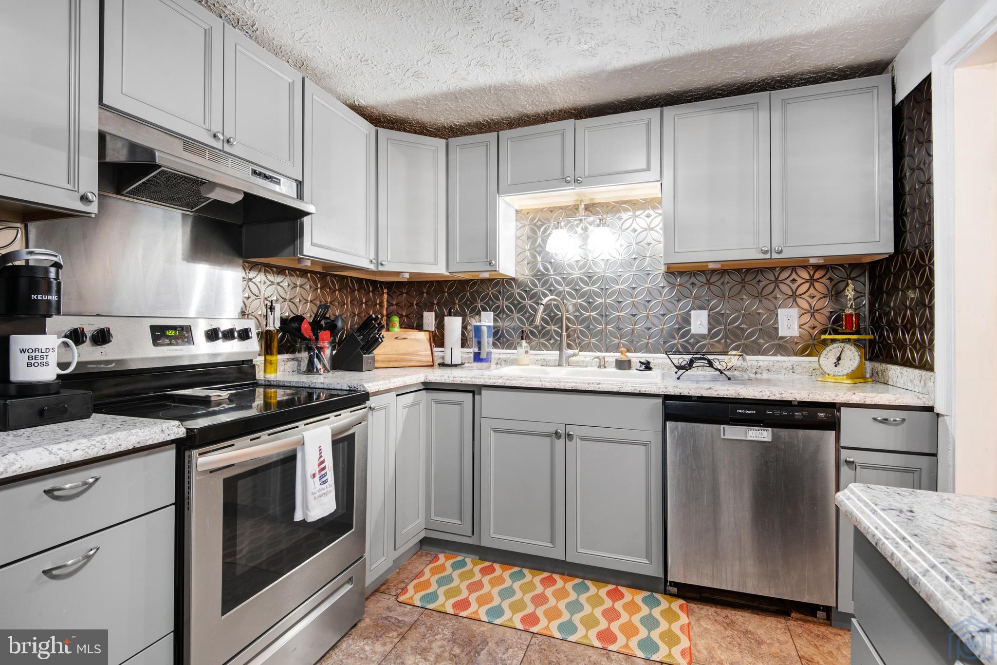 a kitchen with stainless steel appliances granite countertop a stove a sink dishwasher and white cabinets with wooden floor