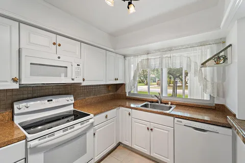 an empty room with wooden floor chandelier fan and windows