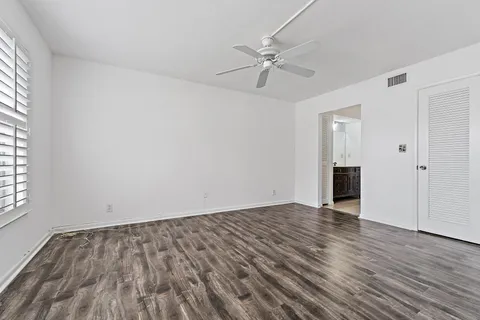 a view of empty room with wooden floor and ceiling fan
