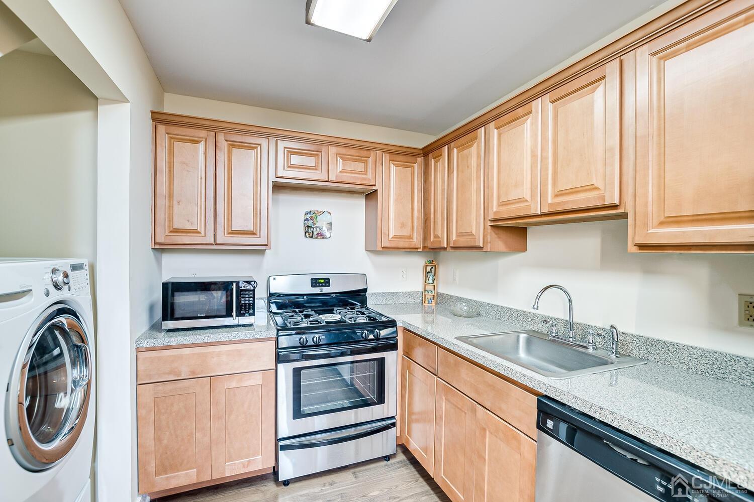 40 Washington Avenue, Unit 9 Milltown, NJ 08850 - Photo 27 of 43 a kitchen with granite countertop a sink a stove a washer and dryer next to a window