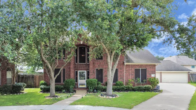 a front view of a house with a yard and a tree