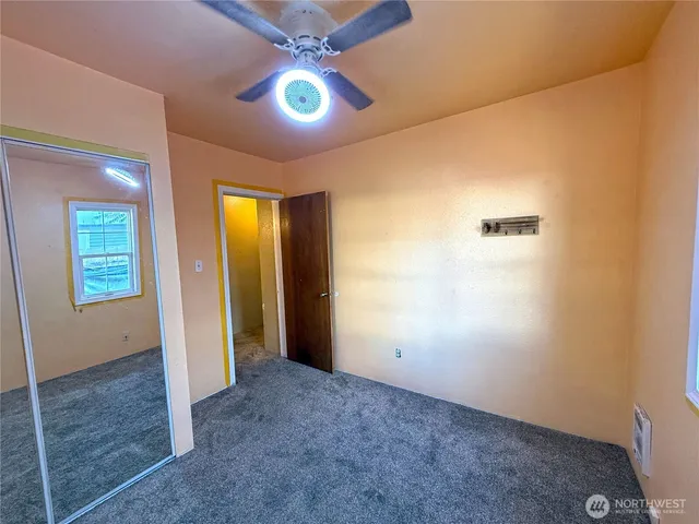 an empty room with windows and chandelier fan