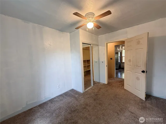 an empty room with closet and a chandelier fan