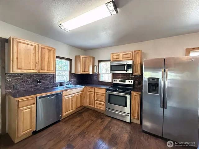 a kitchen with stainless steel appliances and wooden floor
