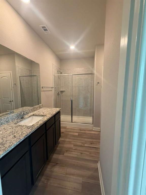 310 Foster Lane Anna, TX 75409 - Photo 15 of 15 Spacious bathroom featuring a double vanity with granite-style countertops, dark wood cabinetry, and a walk-in shower with a glass enclosure