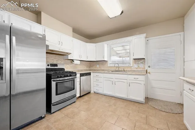 a kitchen with granite countertop white cabinets and stainless steel appliances